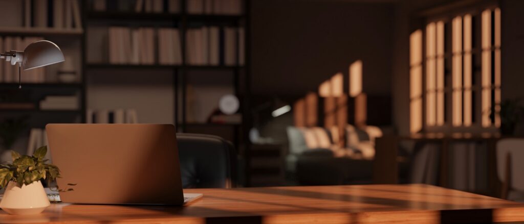 A home office with a laptop, table lamp and decor on a wooden desk