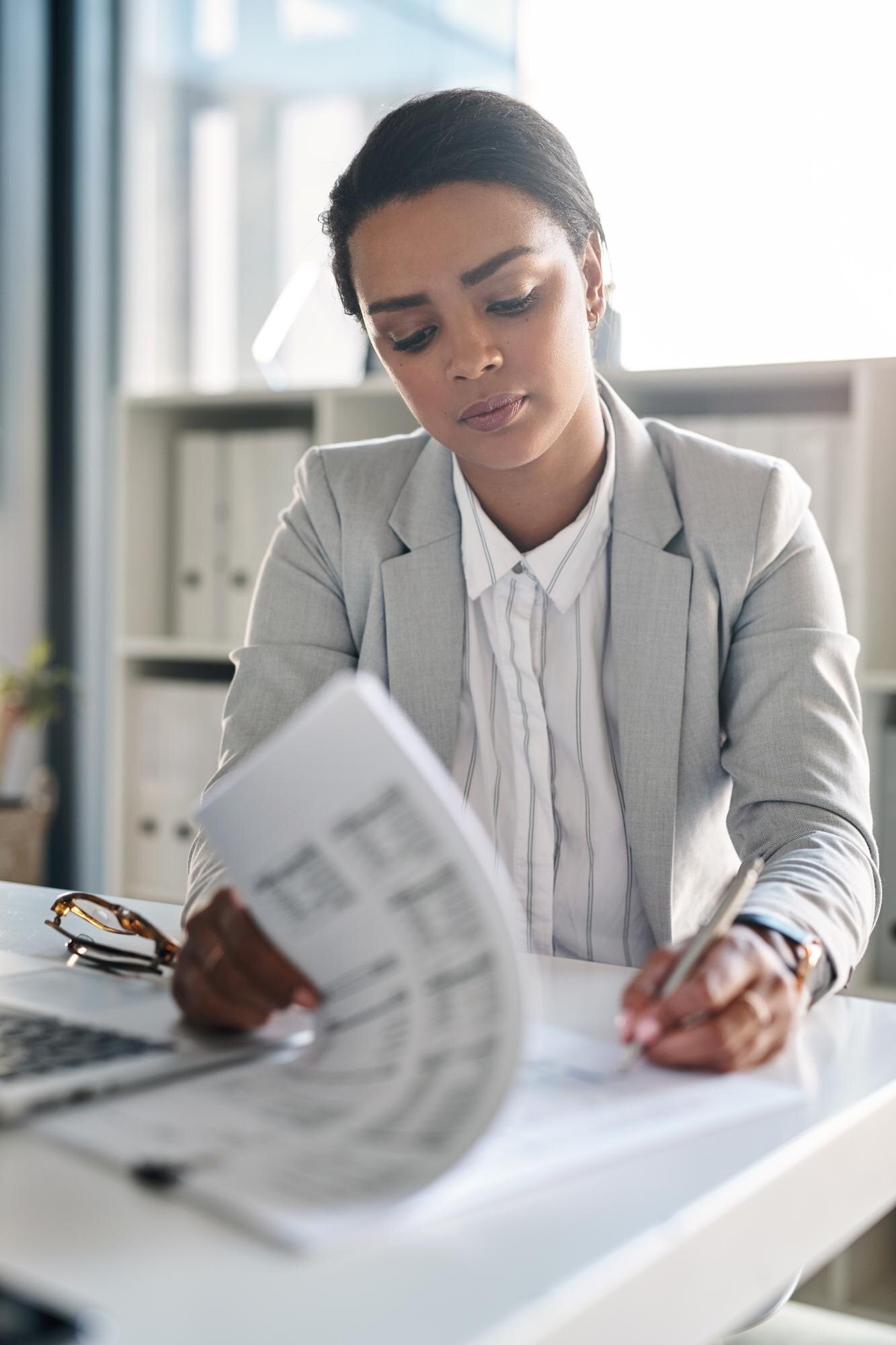 A businesswoman reading paperwork at an office desk
