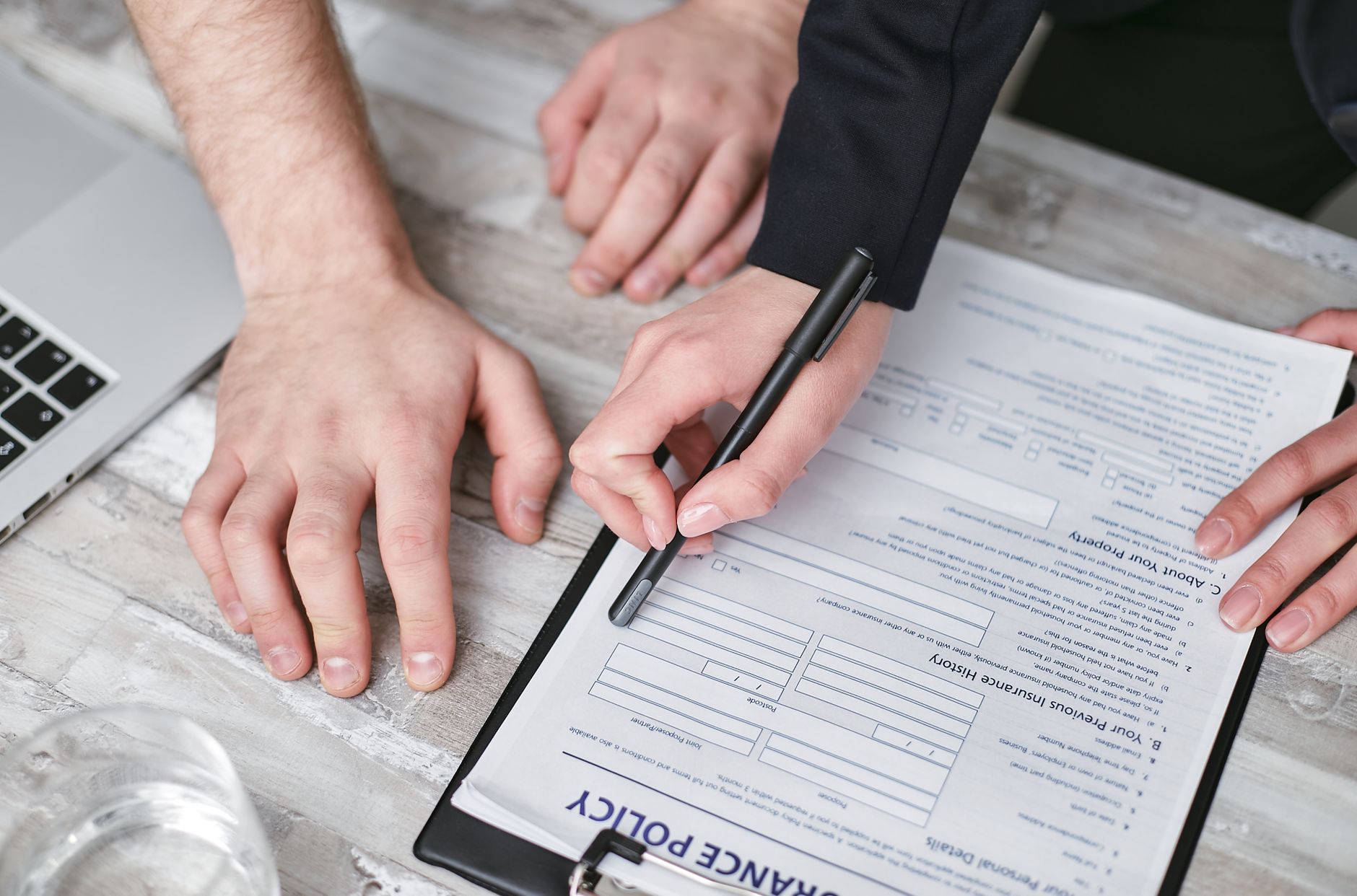 Two people reviewing and signing an insurance policy document at a desk