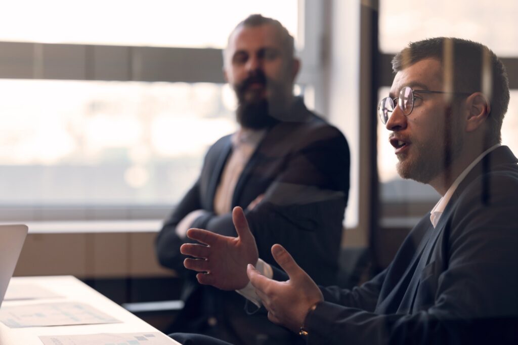 Two professionals in discussion across a table in a modern office